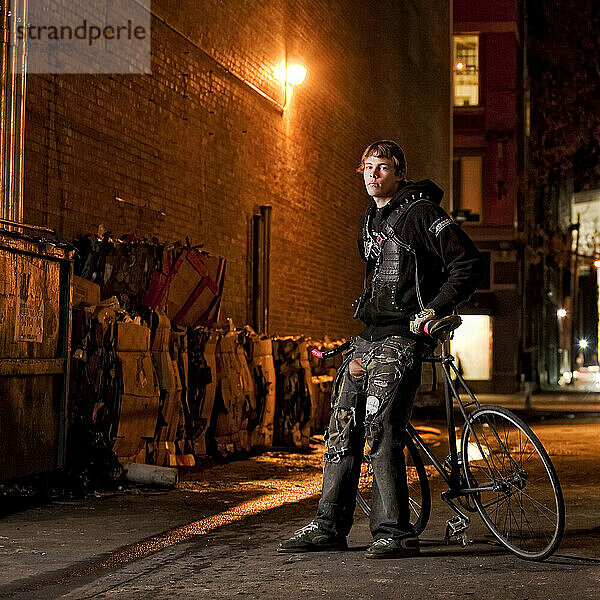 Der Fixed Gear Rider posiert mit seinem Fahrrad in einem dunklen Verbündeten.