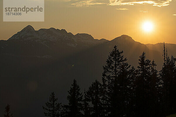 Malerische Aussicht auf den Sonnenuntergang über den Berggipfeln an einem Frühlingstag.