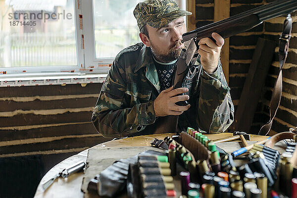 Vorderansicht eines Mannes  der das Visier seiner Schrotflinte überprüft  während er sich auf einen Jagdausflug vorbereitet  Tichwin  Sankt Petersburg  Russland