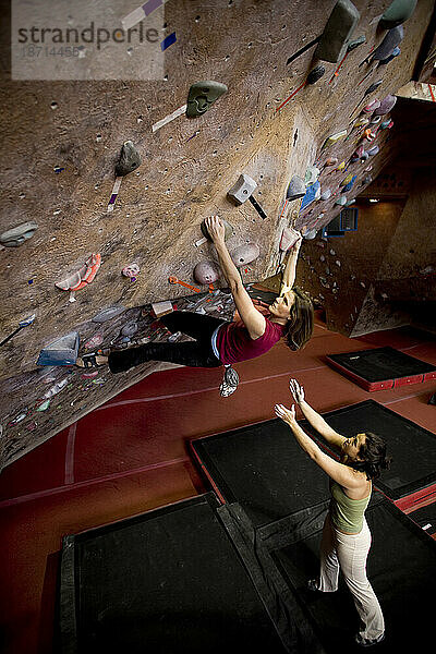 Klettererinnen bouldern in einer Kletterhalle.