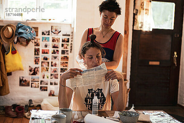 Queeres Paar liest Anweisungen für Haarbleiche im heimischen Friseursalon