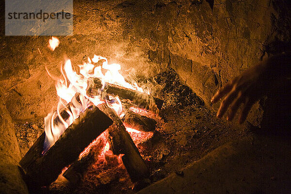 Ein Mann wärmt seine Hände am Abendfeuer im Bluebell-Tierheim im Chautauqua Park  Boulder  Colorado.