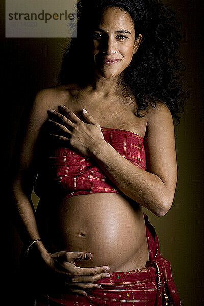 Ein Porträt einer lächelnden Frau  die im siebten Monat schwanger ist.