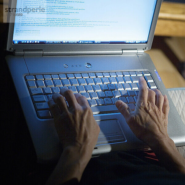 Blick auf die Hände einer Frau auf der Tastatur eines Laptops.