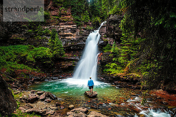 Mann am bewaldeten Wasserfall in den Colorado Mountains
