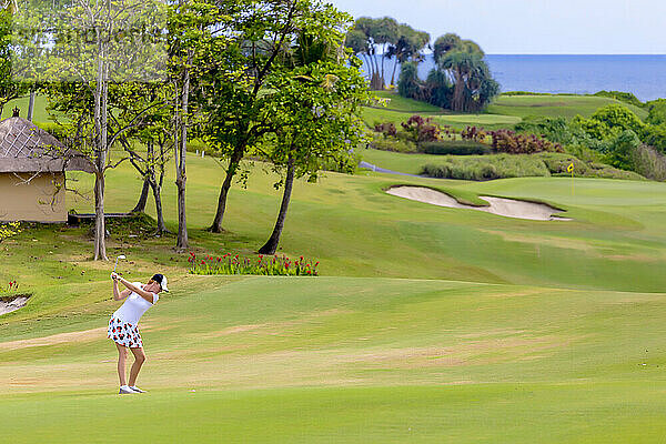 Junge Frau spielt an einem sonnigen Tag Golf