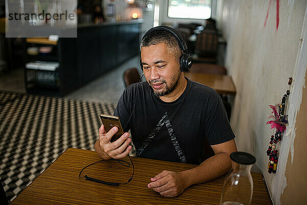 Asiatischer Mann hört Musik über Kopfhörer
