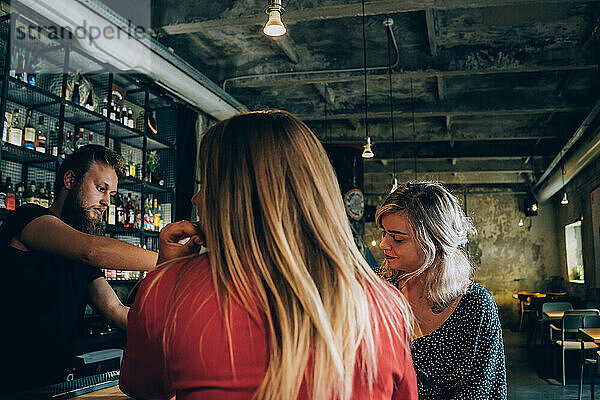 Zwei Freunde und Barmann in einer Cocktailbar.