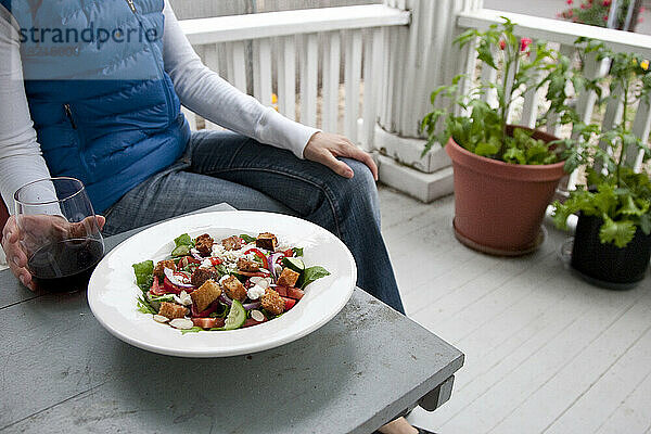 Eine Frau bereitet sich darauf vor  einen Salat aus Zutaten in ihrem Garten zu essen.