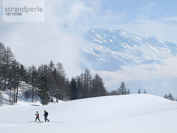 Zwei Winterwanderer wandern auf dem Hochplateau der Moosalp in den Schweizer Walliser Alpen.