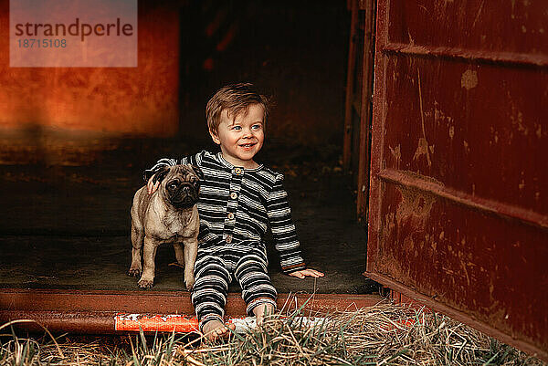 Baby-Kleinkind mit einem Mops-Welpen im Sitzen