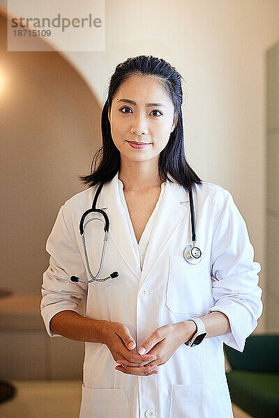 Porträt einer Ärztin im Laborkittel  während sie in der Klinik steht