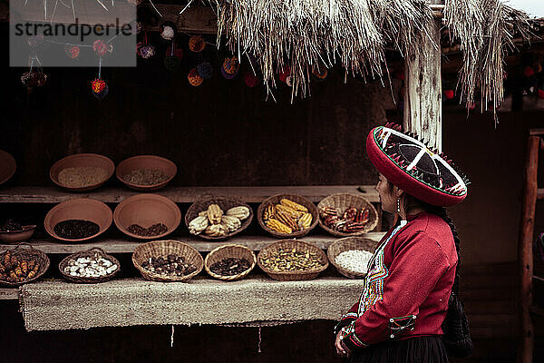 Einheimische Frau in traditioneller Kleidung steht mit Körben mit lokalen Lebensmitteln