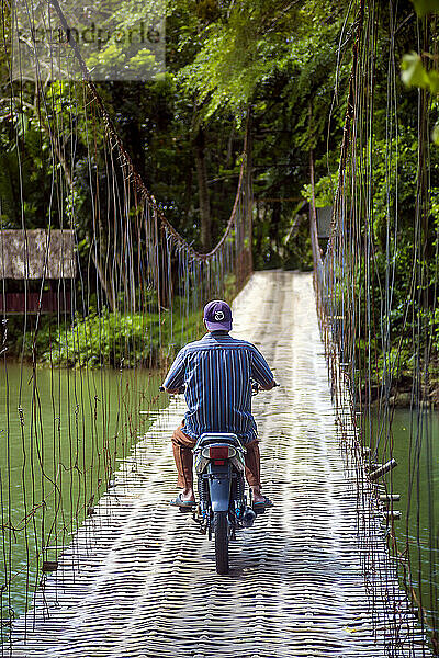 Mann fährt Motorrad auf Hängebrücke