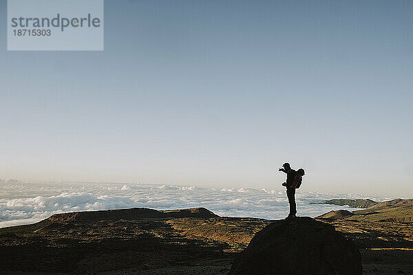 Silhouette eines männlichen Wanderers  der auf eine Vulkanlandschaft zeigt