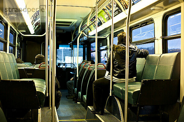 Eine Frau sitzt allein in einem Bus in Seattle  Washington  während der Bus in der Abenddämmerung durch den Verkehr fährt.