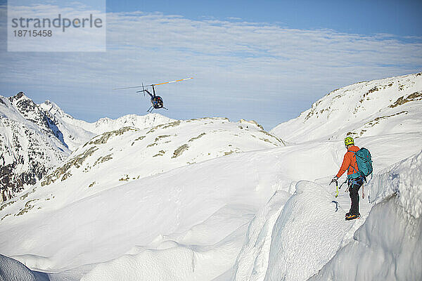 Mann steuert Hubschrauber auf schneebedecktem Berg