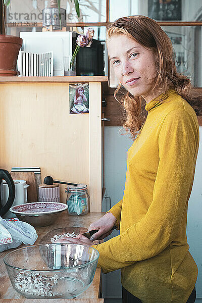 Schöne Frau lächelt friedlich und schneidet Gemüse in der Küche zu Hause