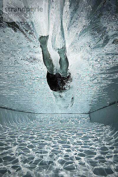 Ein Mann springt in einen Pool  um Bahnen zu schwimmen.