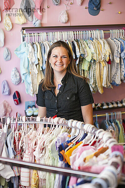 Eine Frau steht zwischen Regalen mit Babykleidung.