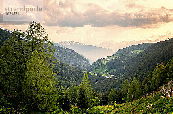 Traumhafter Blick auf das Alpental mit Bäumen und Wolken in der Abenddämmerung