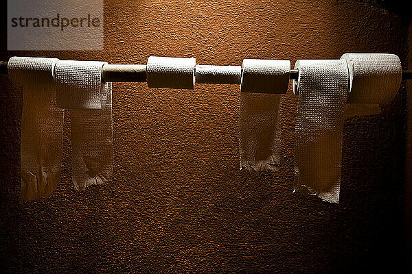 Licht scheint auf Toilettenpapierrollen in einem orangefarbenen Badezimmer.