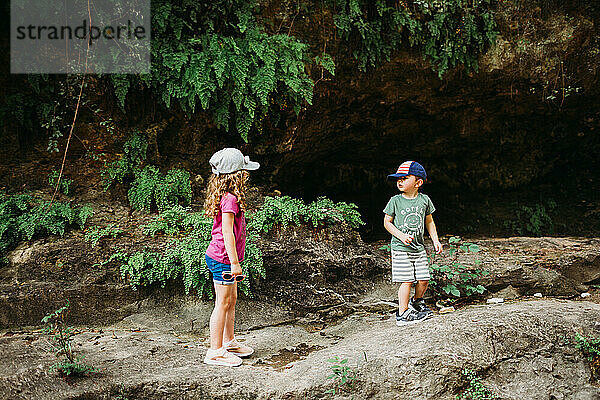 Junge und Mädchen klettern beim Wandern auf Felsbrocken