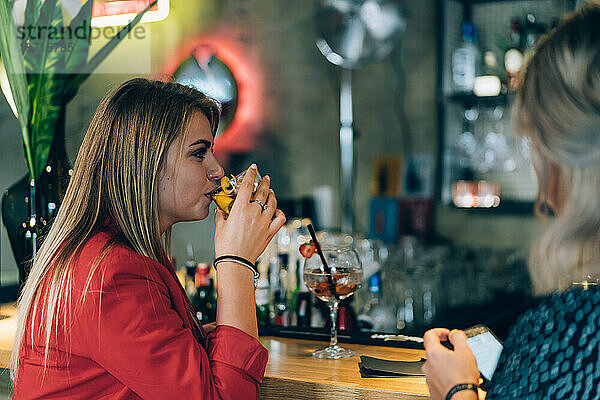 Blondes Mädchen trinkt in einer Bar.