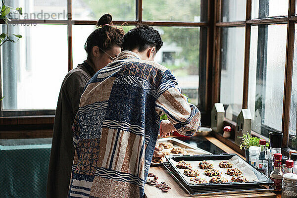 Paar zu Hause in der Küche backt hausgemachte Kekse mit Pekannüssen