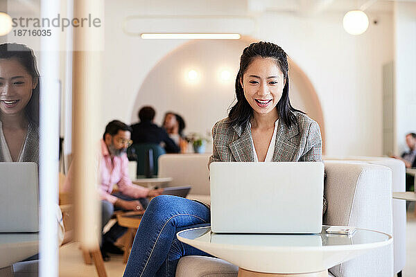 Lächelnde Unternehmerin  die im Büro am Laptop arbeitet