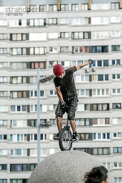 Ein Teenager  der auf einer Steinkugel Einrad fährt  erfordert sorgfältiges Gleichgewicht