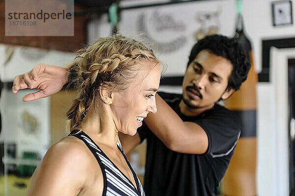 Junge Frau erhält Hilfe beim Dehnen von einem Trainer im Fitnessstudio  Seminyak  Bali  Indonesien
