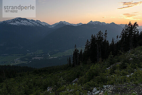Malerische Aussicht auf den Sonnenuntergang über den Berggipfeln und dem Tal an einem Frühlingstag.
