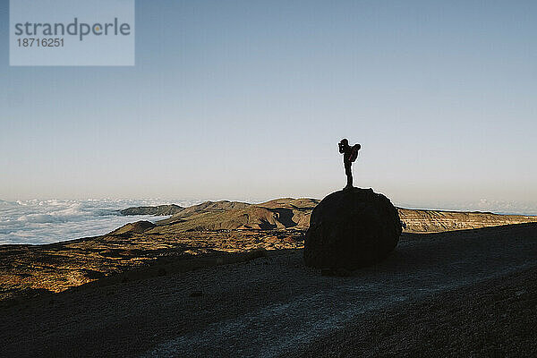 Silhouette eines männlichen Wanderers  der eine vulkanische Landschaft fotografiert