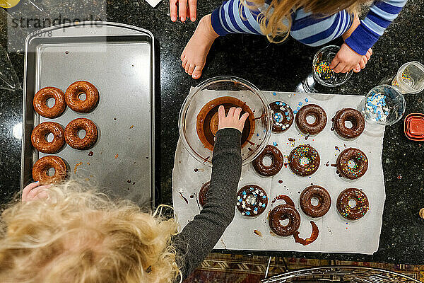 Draufsicht auf Kinder  die zu Hause auf der Küchentheke Donuts backen