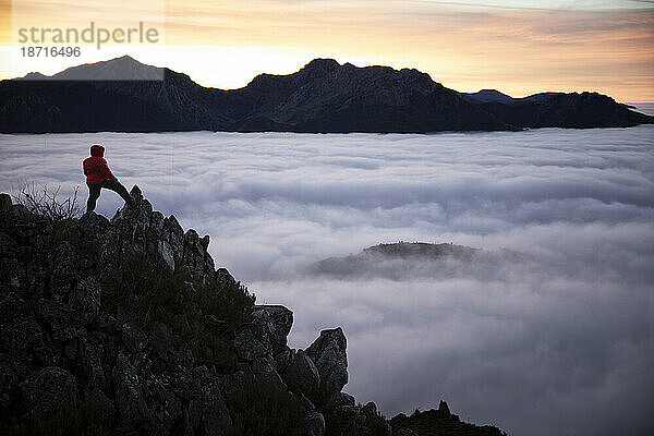 Der Mensch beobachtet Nebel bei Sonnenaufgang von der Spitze einiger Berge aus