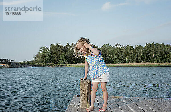 Ein junges Mädchen stand auf einem Steg und blickte auf das Wasser am Strand
