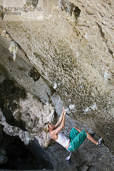 Eine Sportlerin klammert sich verzweifelt an ihr Leben  während sie in Thailand ein Boulderproblem löst. Wunderschöner Kalksteinfelsen mit vielen schönen Griffen.