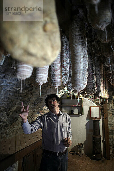 Ein Mann zeigt seinen Keller mit Wurstwaren auf dem Touristenbauernhof seiner Familie in Slowenien.