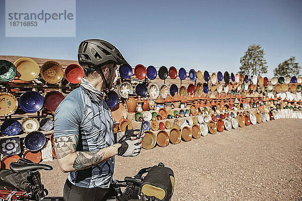 Ein männlicher Radfahrer hält neben einem Outdoor-Keramikmarkt in Marokko