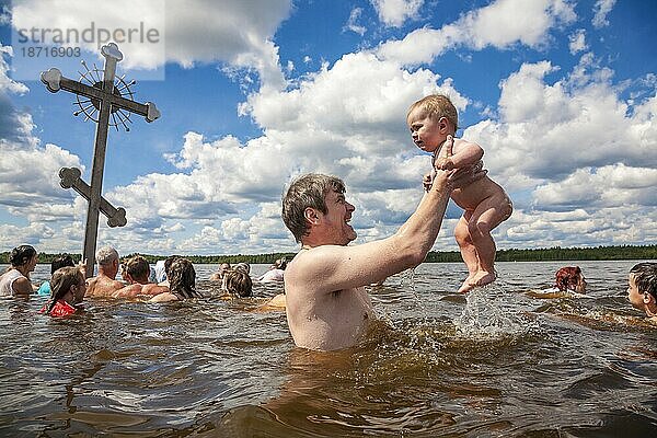 Ein Mann hebt sein Kind aus dem eisigen Seewasser im Tichwin-See  Russland