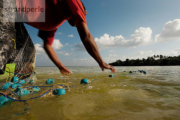 Eine Fischerfamilie entleert ihre Netze am Ufer.