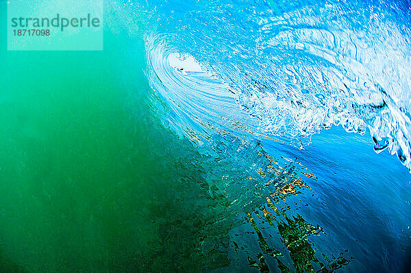 Wasserwinkelansicht einer Surferperspektive in einem hohlen Rohr  das aus einer brechenden Welle herausschaut.