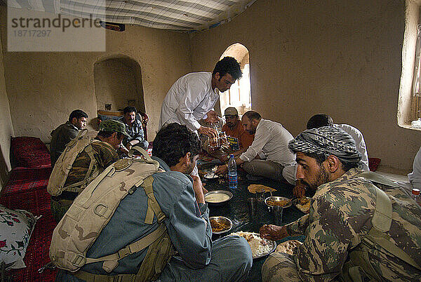 Ein Wildtierbeobachtungsteam und seine Polizeieskorte essen im Gästezimmer des Schulleiters im Dorf Chakhosaini nahe der Grenze zu Turkmenistan zu Mittag