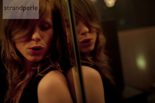 Eine junge Frau tanzt lustvoll mit sich selbst neben einem Spiegel in einem Karaoke-Raum in Koreatown  Los Angeles  Kalifornien.