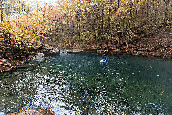 Frau paddelt in einer Herbstszene auf einem klaren Fluss