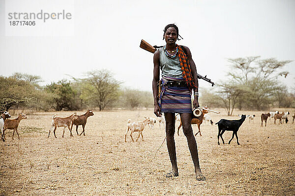 Ein Ziegenhirte schiebt seine Herde mit einem Gewehr auf dem Rücken durch die Wüste im Süden Äthiopiens.