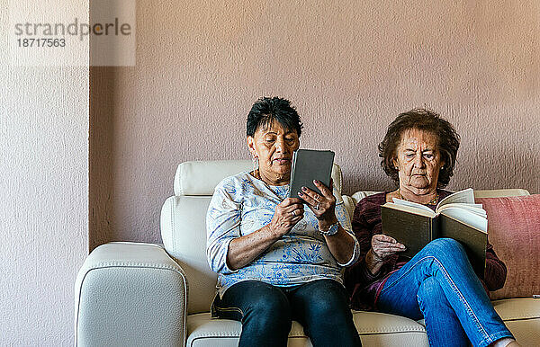 Zwei ältere Frauen kaufen ein und lesen ein elektronisches Buch und ein Papierbuch