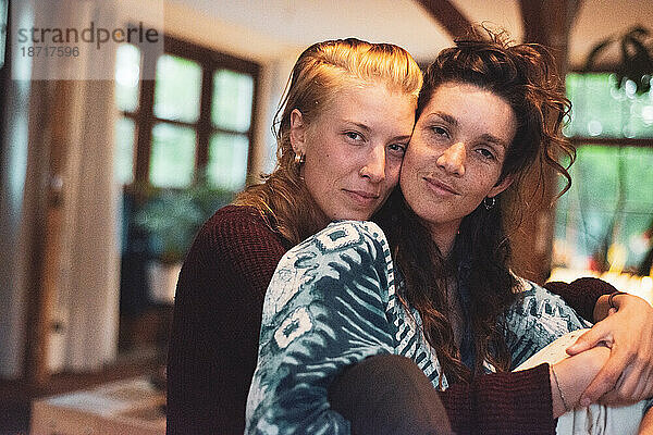 Porträt eines schönen lesbischen Paares  das in einem hellen Holzhaus kuschelt