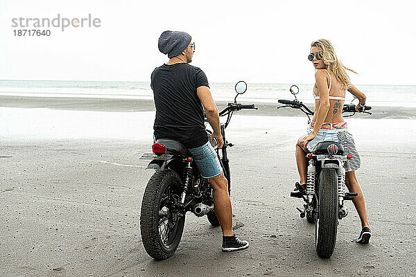 Hipster-Paar fährt Motorrad am Strand.